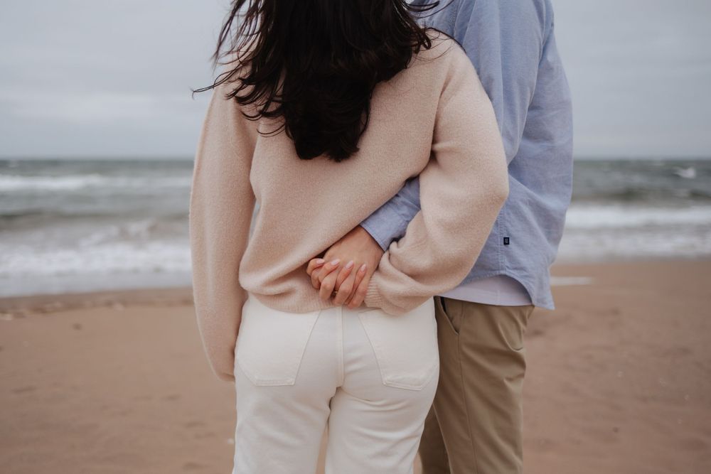 A couple embraces tenderly on a misty beach shore.