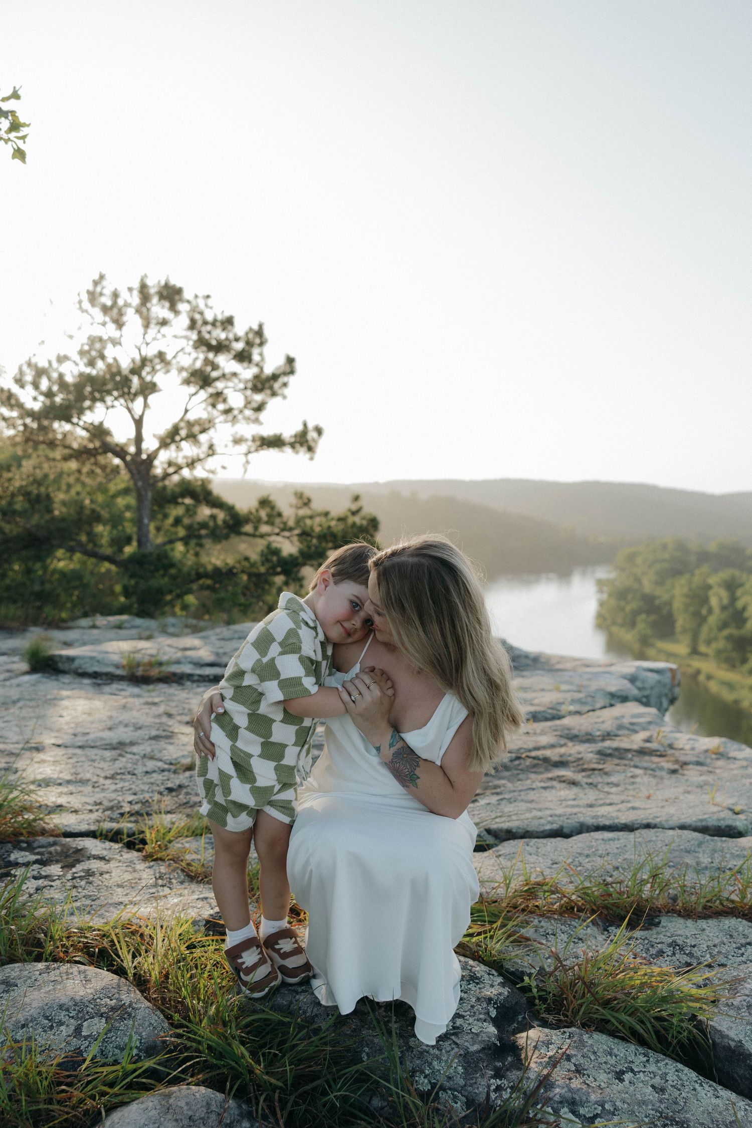 Two people in yellow dresses embrace on a red clay landscape at sunset.