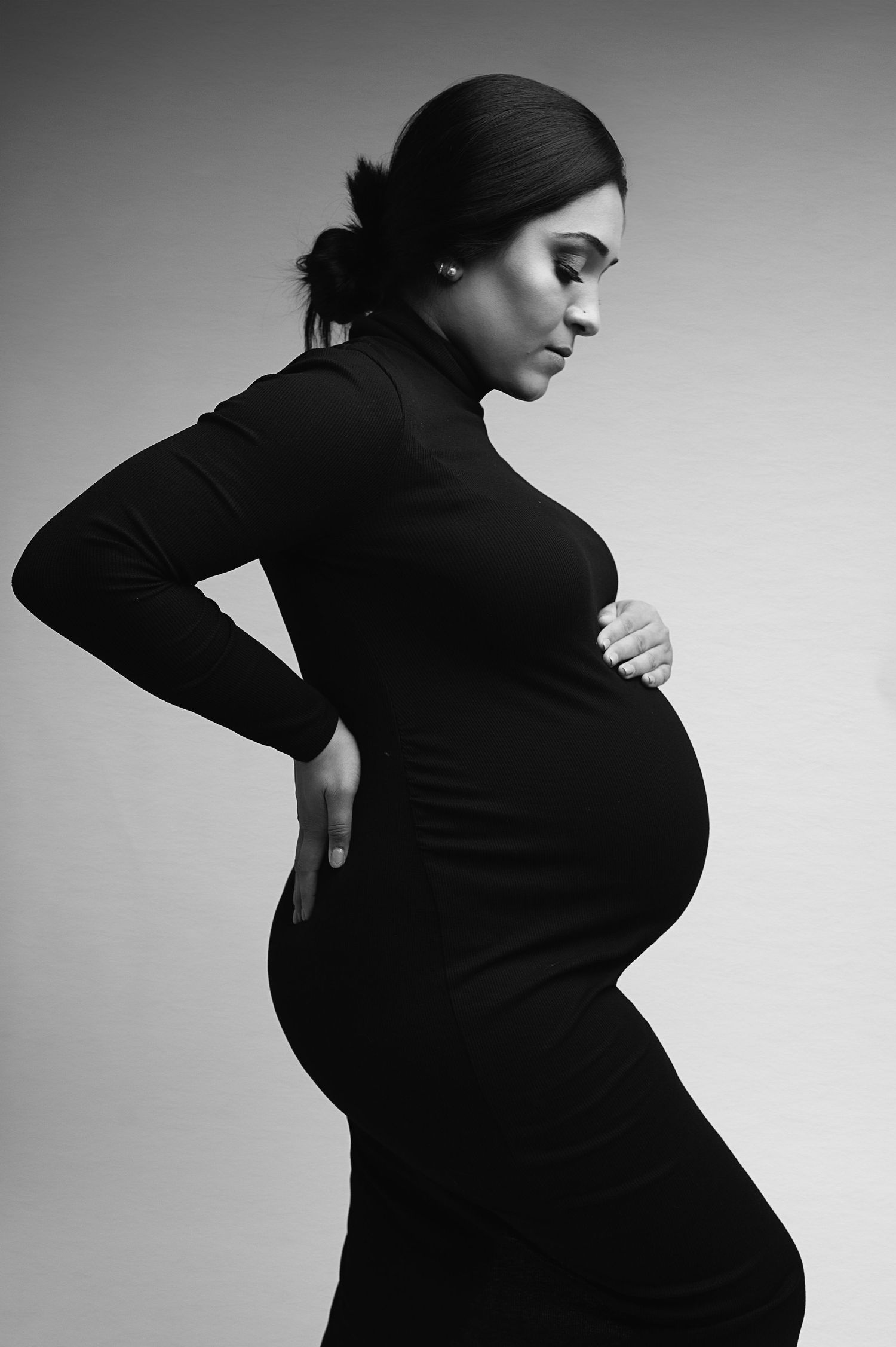 Artistic black and white maternity portrait showing silhouette in fitted dress.