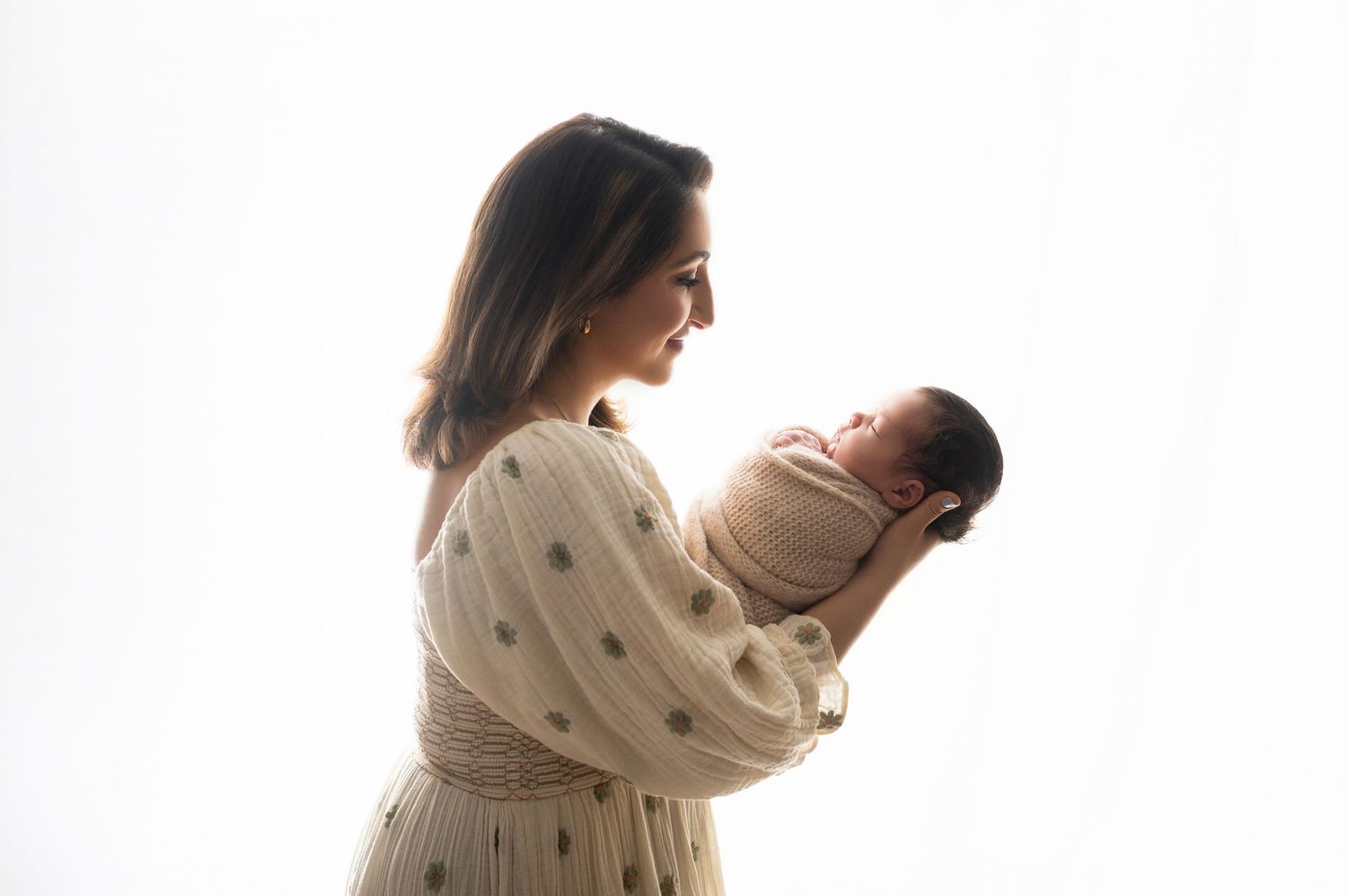 Gentle family moment captured in silhouette against white studio background.