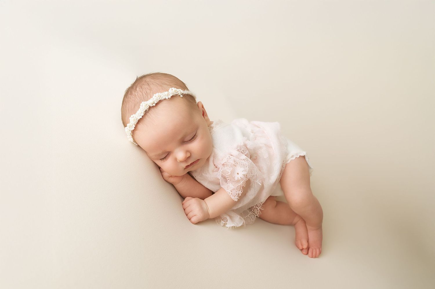 Delicate newborn photography with baby in white lace outfit.