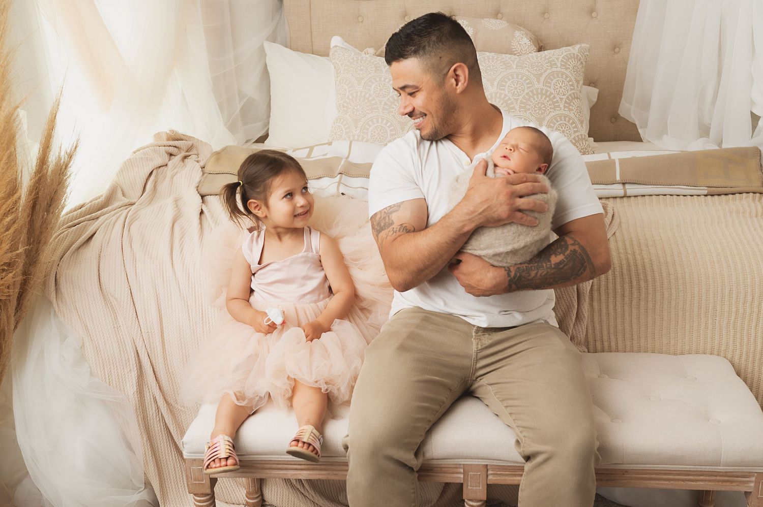 Family portrait of father with two children sitting on cream couch in gentle natural light.