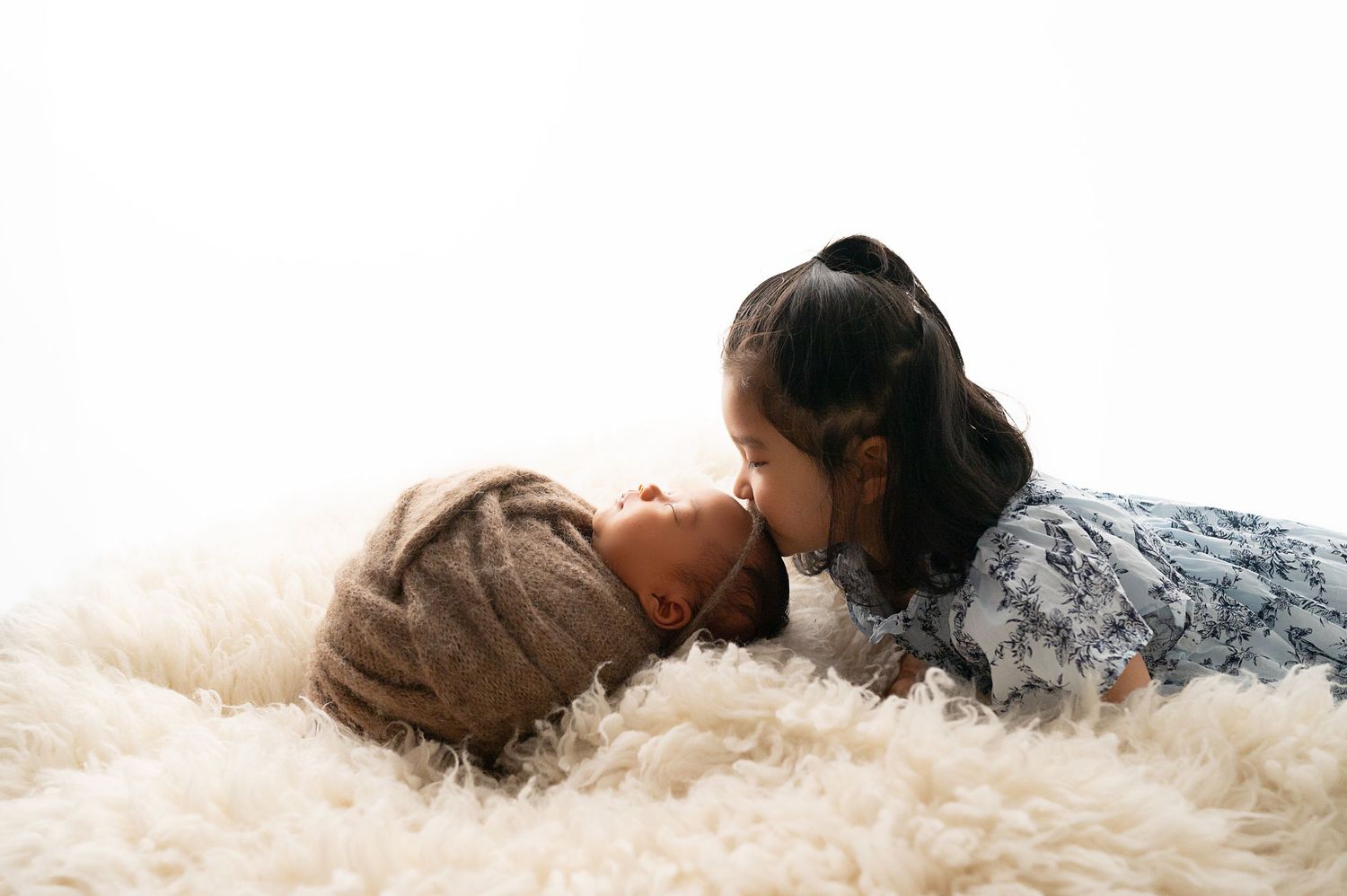 Two siblings sharing an intimate moment on fluffy white carpet.