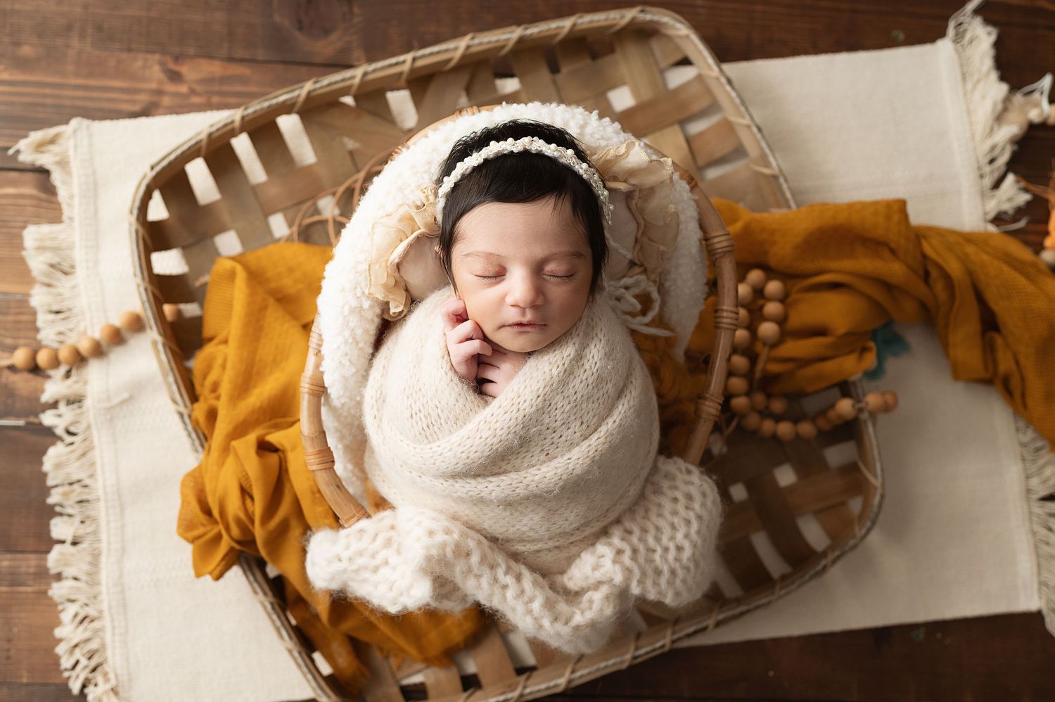 Newborn photography setup with cream and mustard colored blankets and textures.