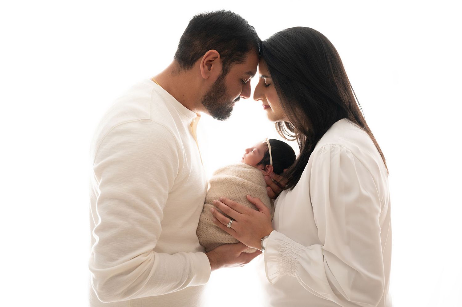 Romantic couple in white outfits sharing intimate moment against white background.