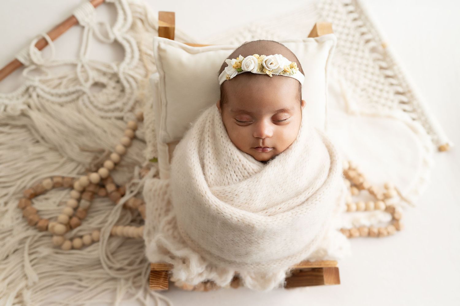 A sleeping newborn wrapped in white linen swaddle with delicate lace details and soft textures.