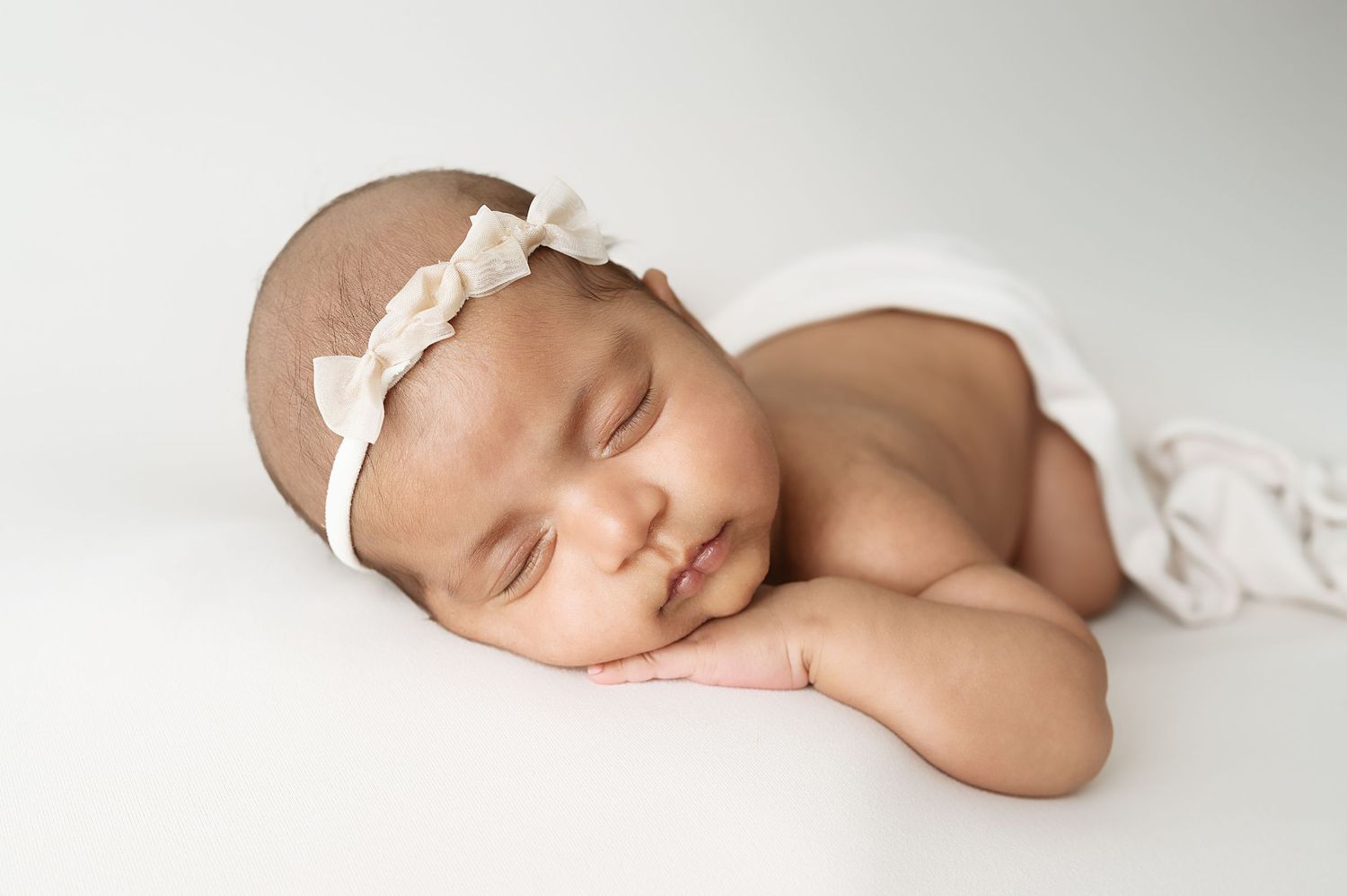 Artistic newborn portrait series with white fabric and minimalist styling.