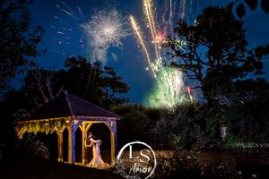 Fireworks illuminate the night sky over an enchanted garden gazebo.