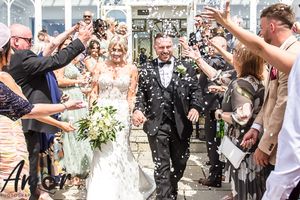 Happy newlyweds walking through rows of guests throwing confetti during joyful wedding exit celebration.
