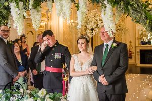 People stand together during an elegant indoor wedding ceremony with floral decor and warm lighting.