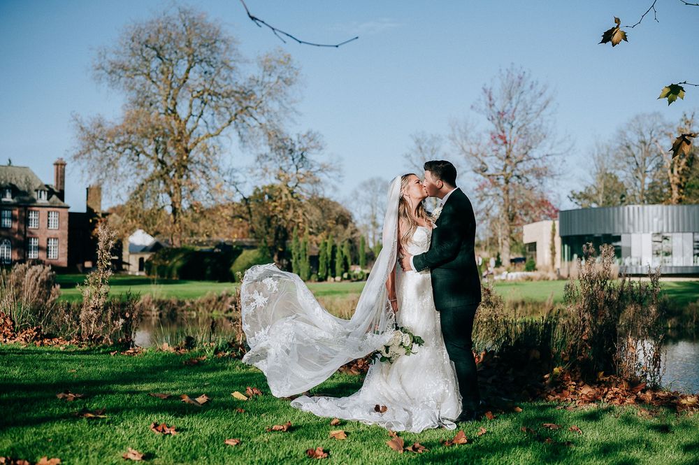 A couple shares a romantic moment in a garden setting as the bride's dress flows elegantly in the breeze.
