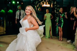 Someone twirls and dances in a sparkly white wedding dress while guests look on at a reception.
