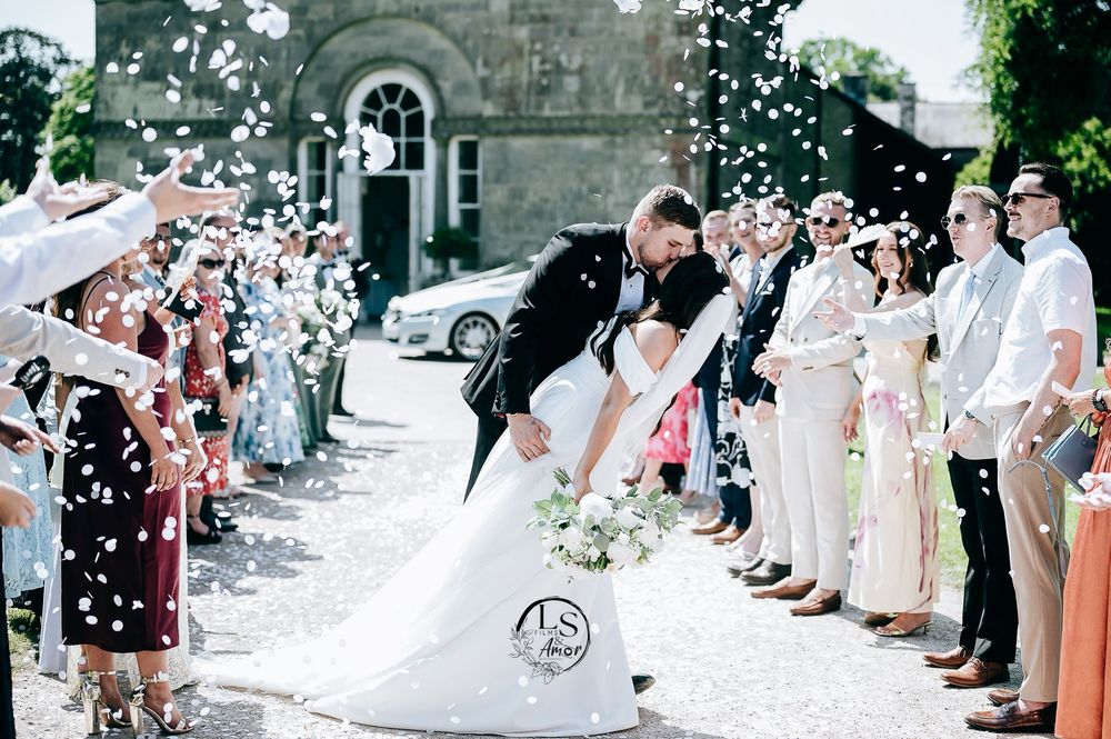 Wedding guests throw confetti at a couple exiting a church after their wedding ceremony.