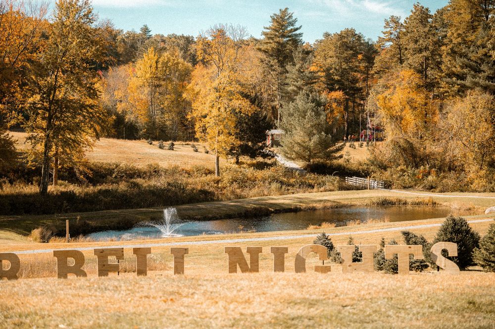 A serene autumn landscape with golden trees reflecting in a tranquil pond while a fountain sprays in the background.