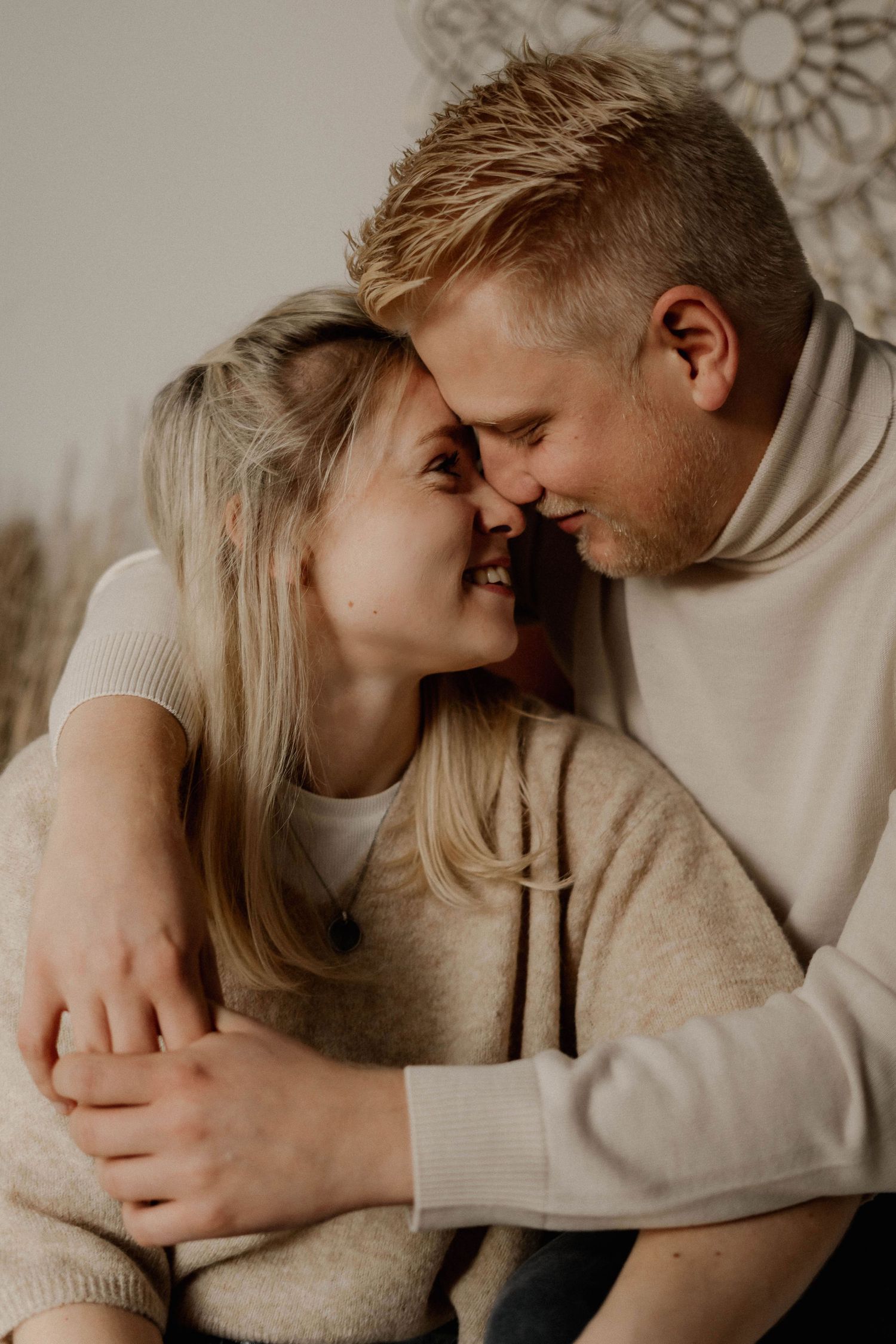 Intimate close-up portrait of couple in neutral sweaters sharing tender moment.
