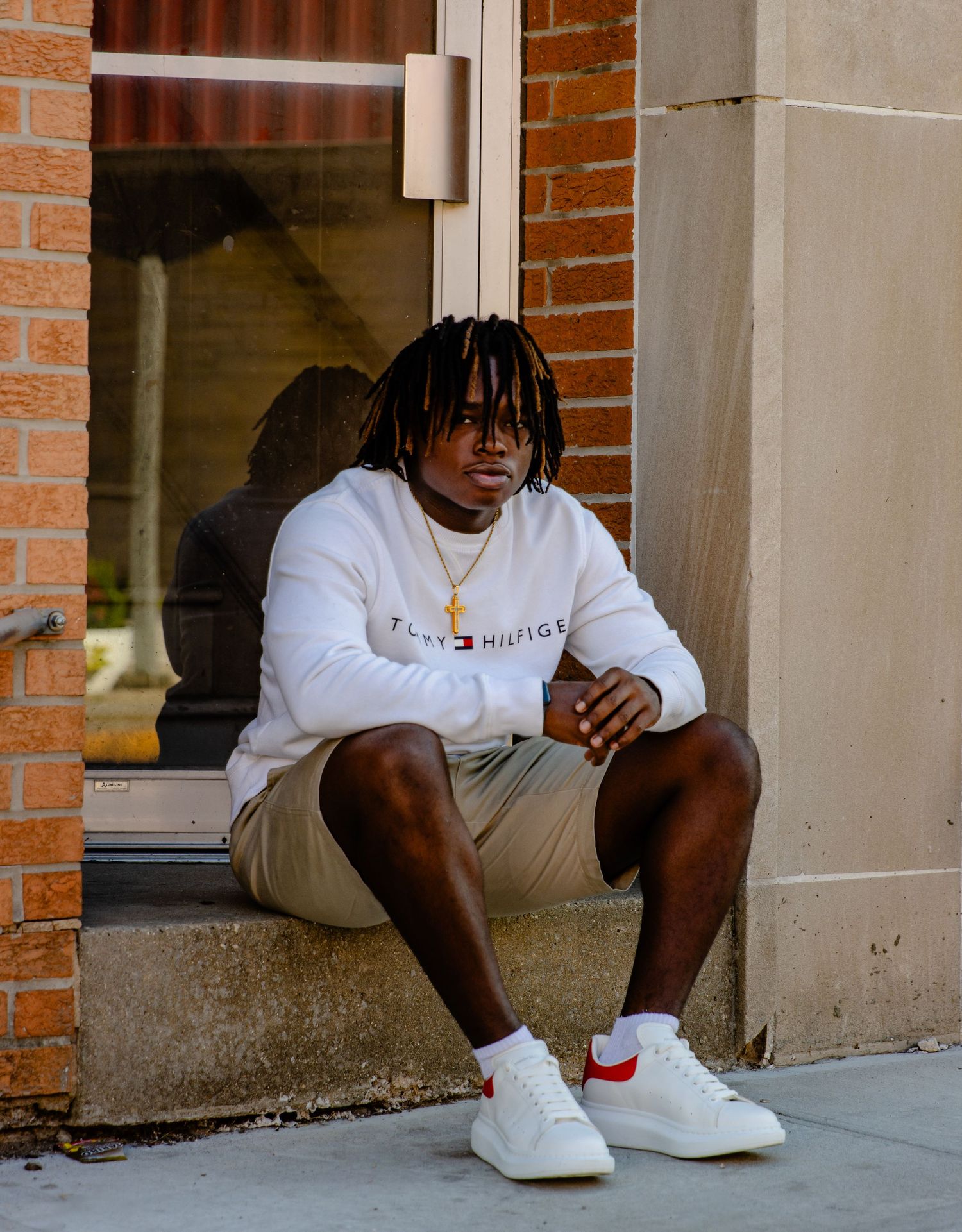 Urban fashion shots featuring someone in white clothing and sneakers sitting on brick building steps.