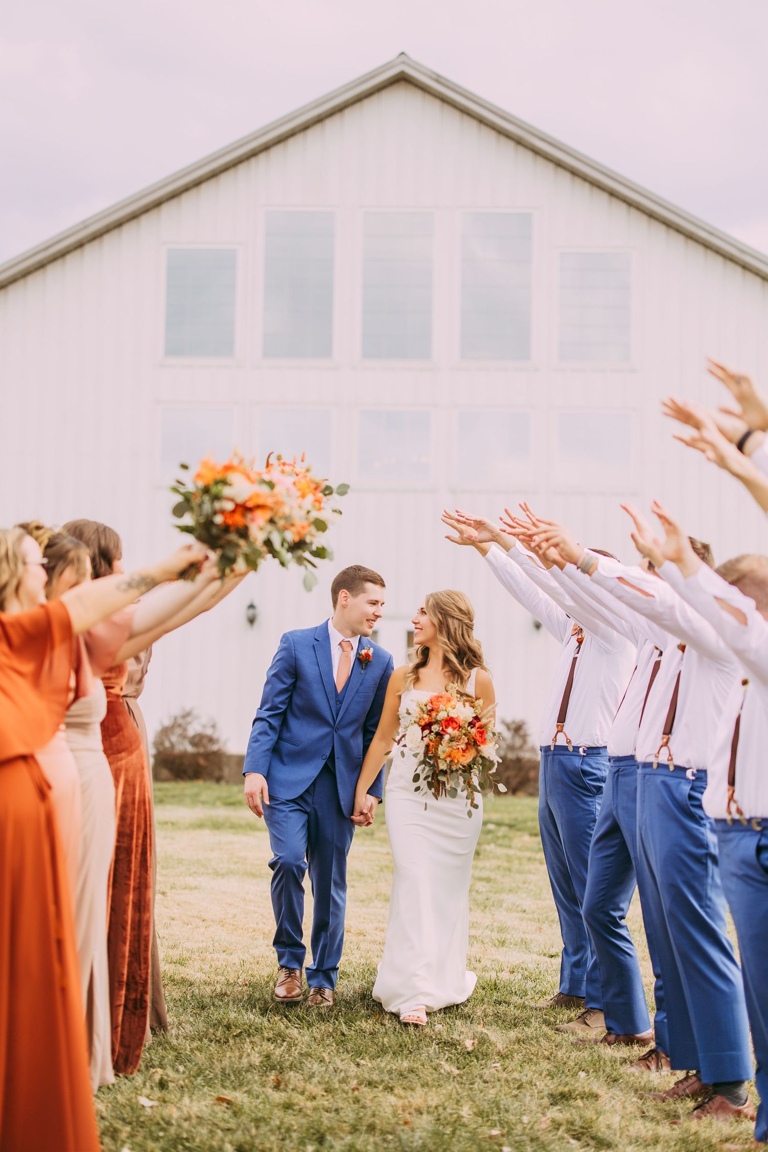 Wedding couple walking through guest tunnel in bright outdoor setting.