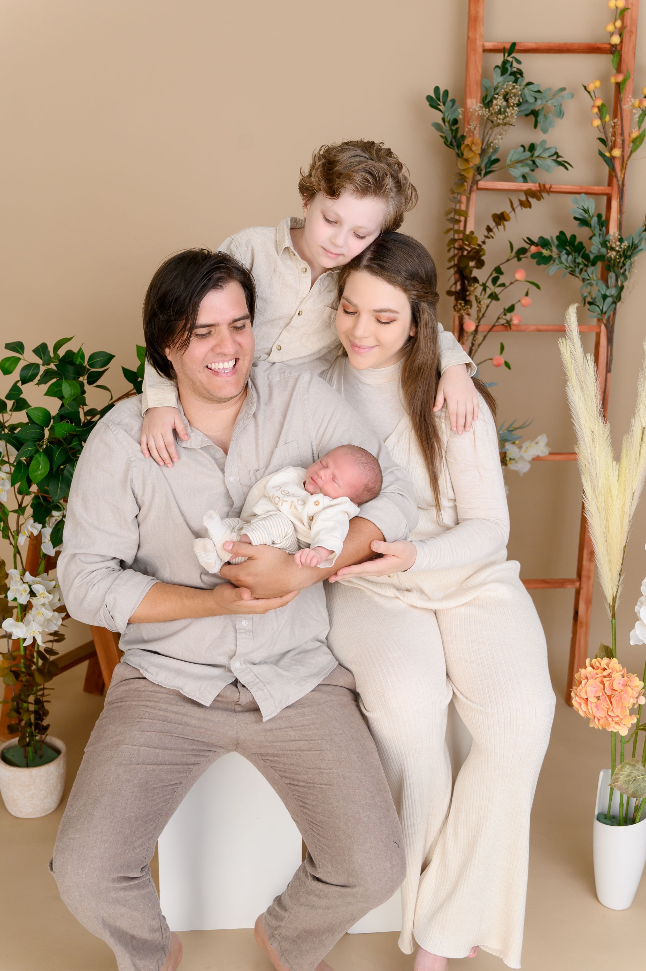 Family bonding with their newborn baby in a cozy room decorated with plants and natural light.