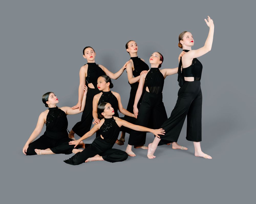 Dancers in black attire perform a series of graceful modern dance movements against a gray studio backdrop.