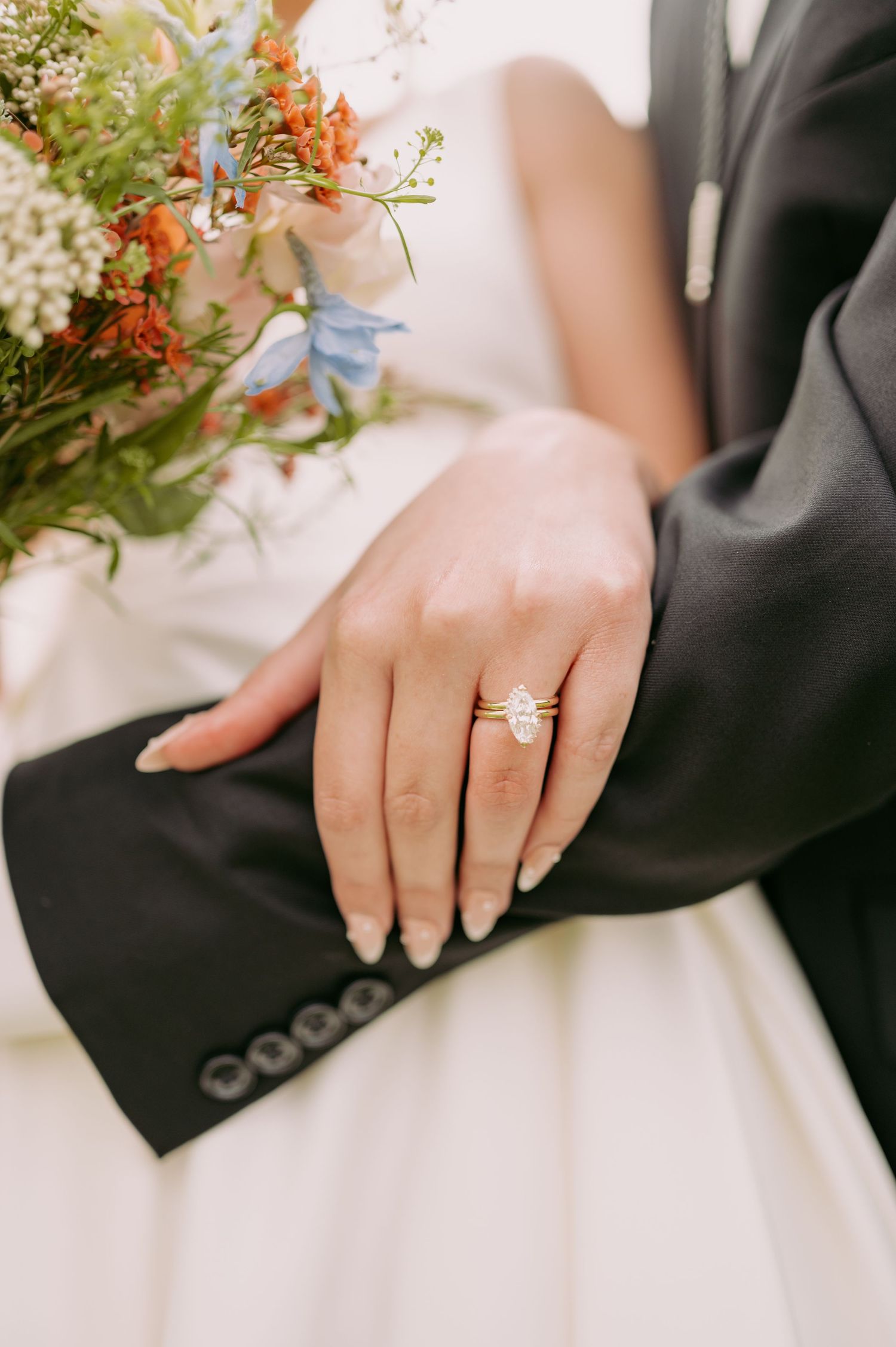Close-up of a sparkling engagement ring with wedding bouquet details in soft focus.