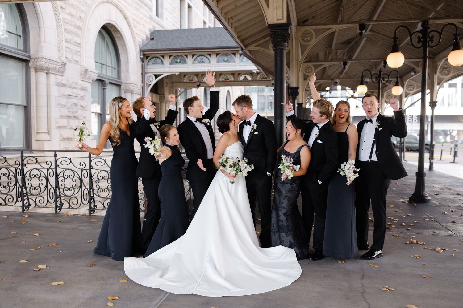 Wedding party creates tunnel with raised arms as newlyweds exit ceremony.