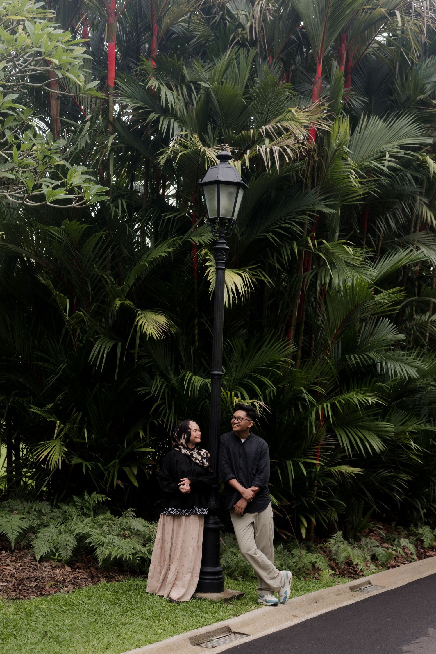 Couple poses together in front of a cascading waterfall wearing coordinated outfits.