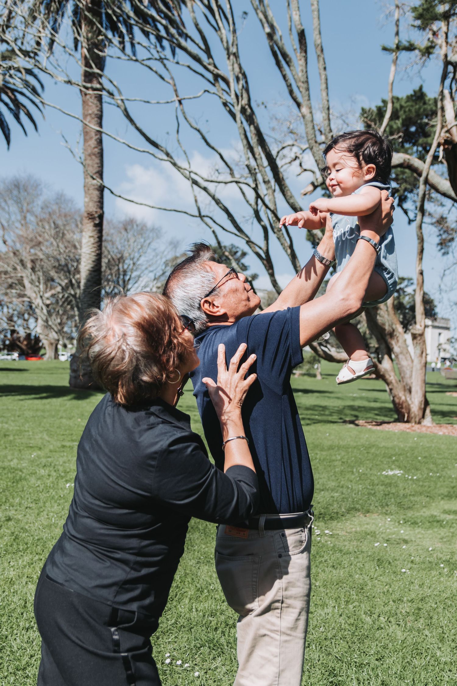 A playful moment in a park as a child is lifted high into the air.