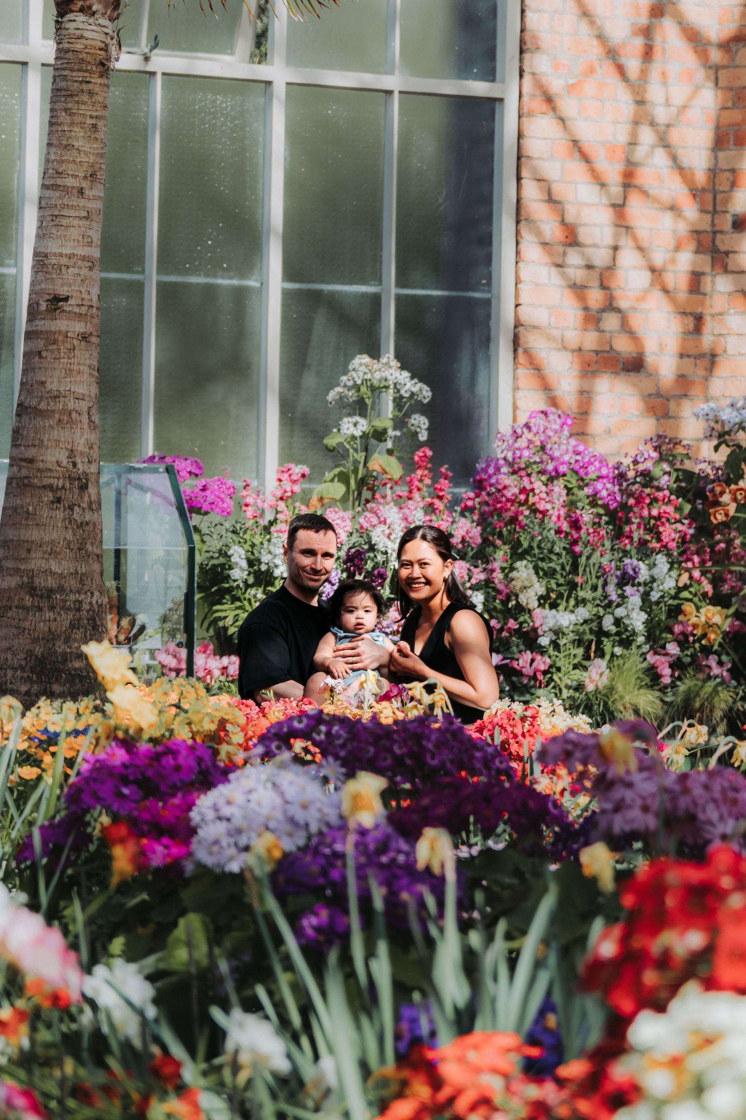 A family portrait surrounded by vibrant spring flowers and colorful garden blooms.