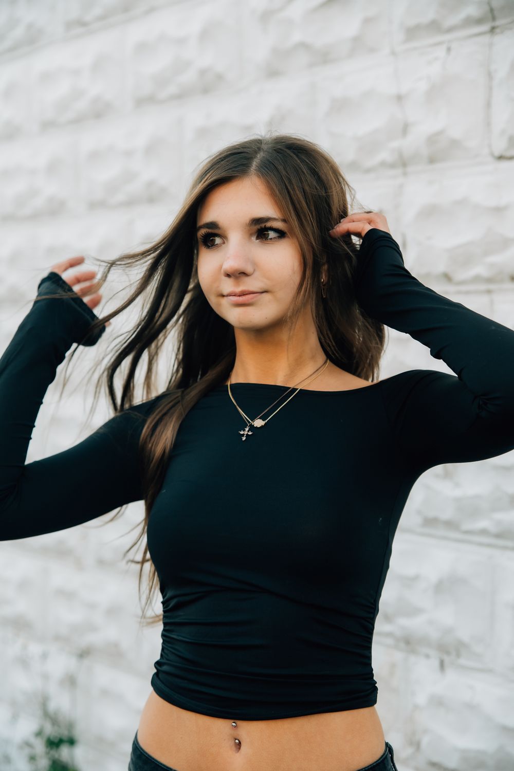A series of dynamic poses in a black crop top against a white wall showing playful movement and hair flips.