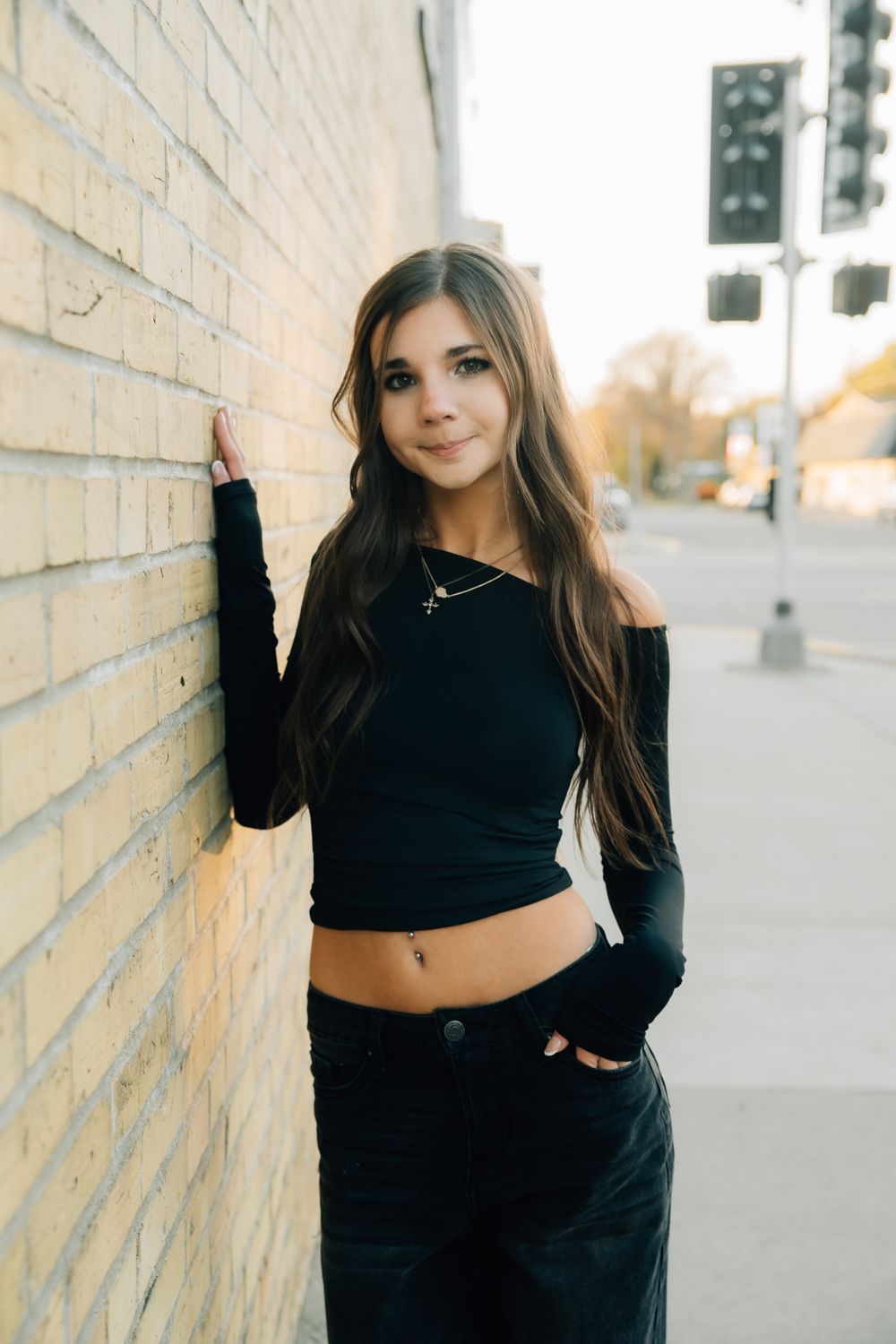Fashion portrait series against a light colored wall showing casual black outfit and natural poses.
