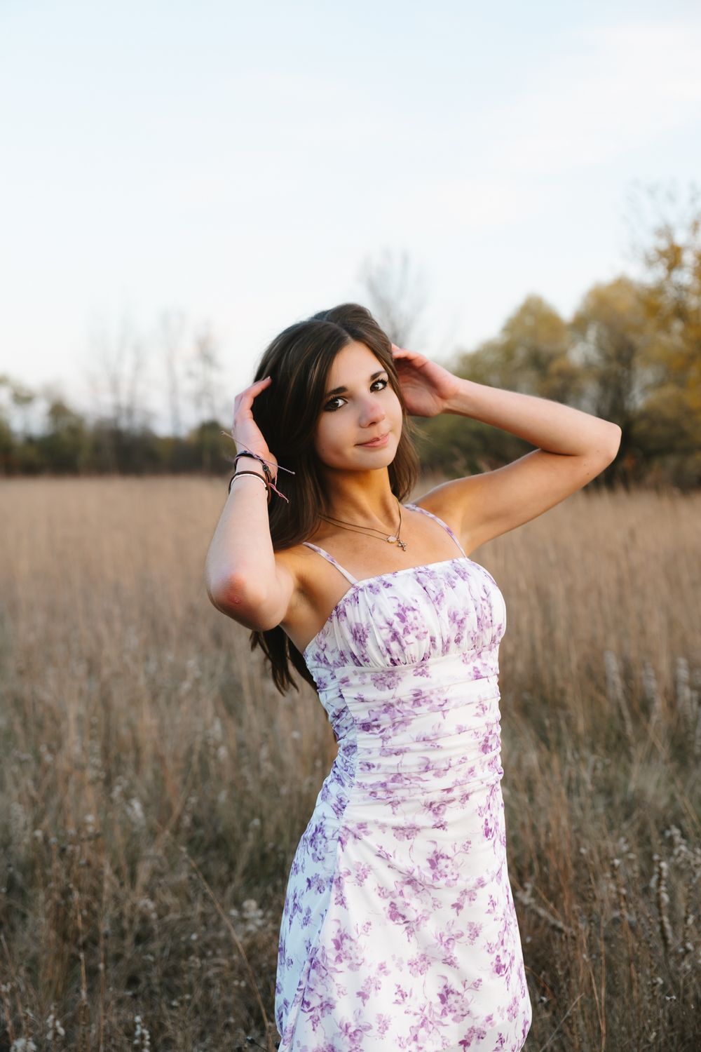A floral dress photoshoot in a golden autumn field with tall grass and warm lighting.