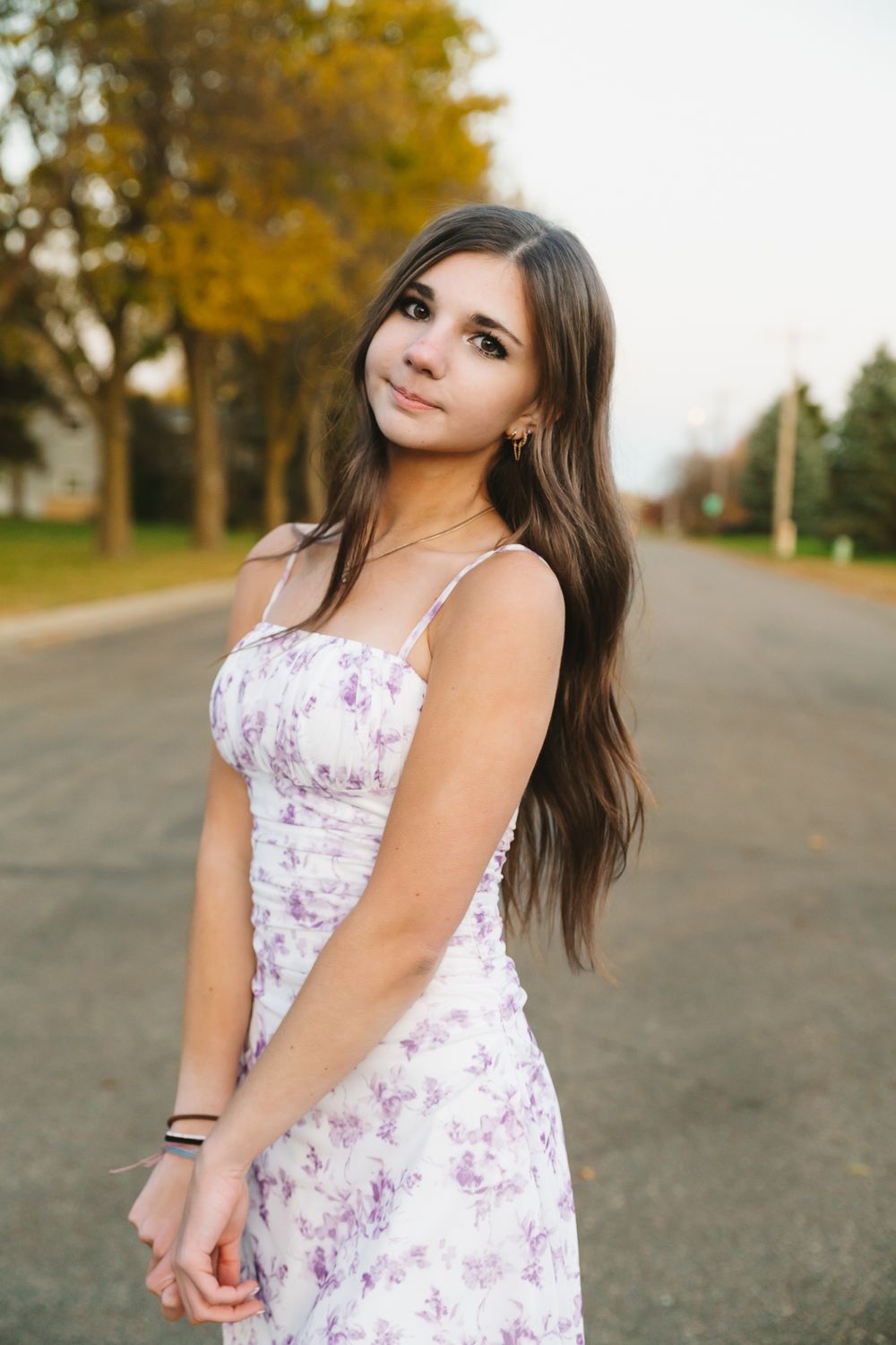 A series of portrait photos in a floral sundress against a fall backdrop with golden trees.