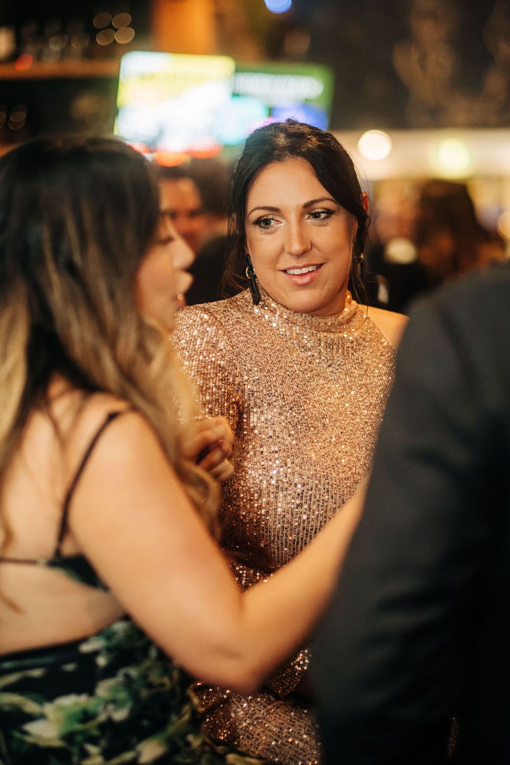 Woman in gold sequin dress socializing at an elegant evening party event.