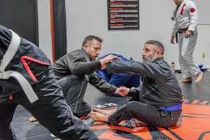 Martial arts students practicing ground fighting techniques during a training session.
