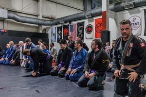Martial arts students sitting in line on mats during a training class.