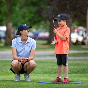 A golf lesson taking place on a practice green with instruction equipment.