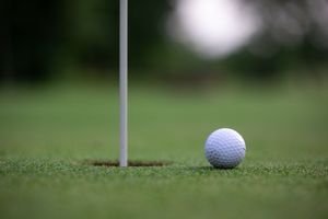 Close-up of a golf ball near the hole pin on a manicured green.