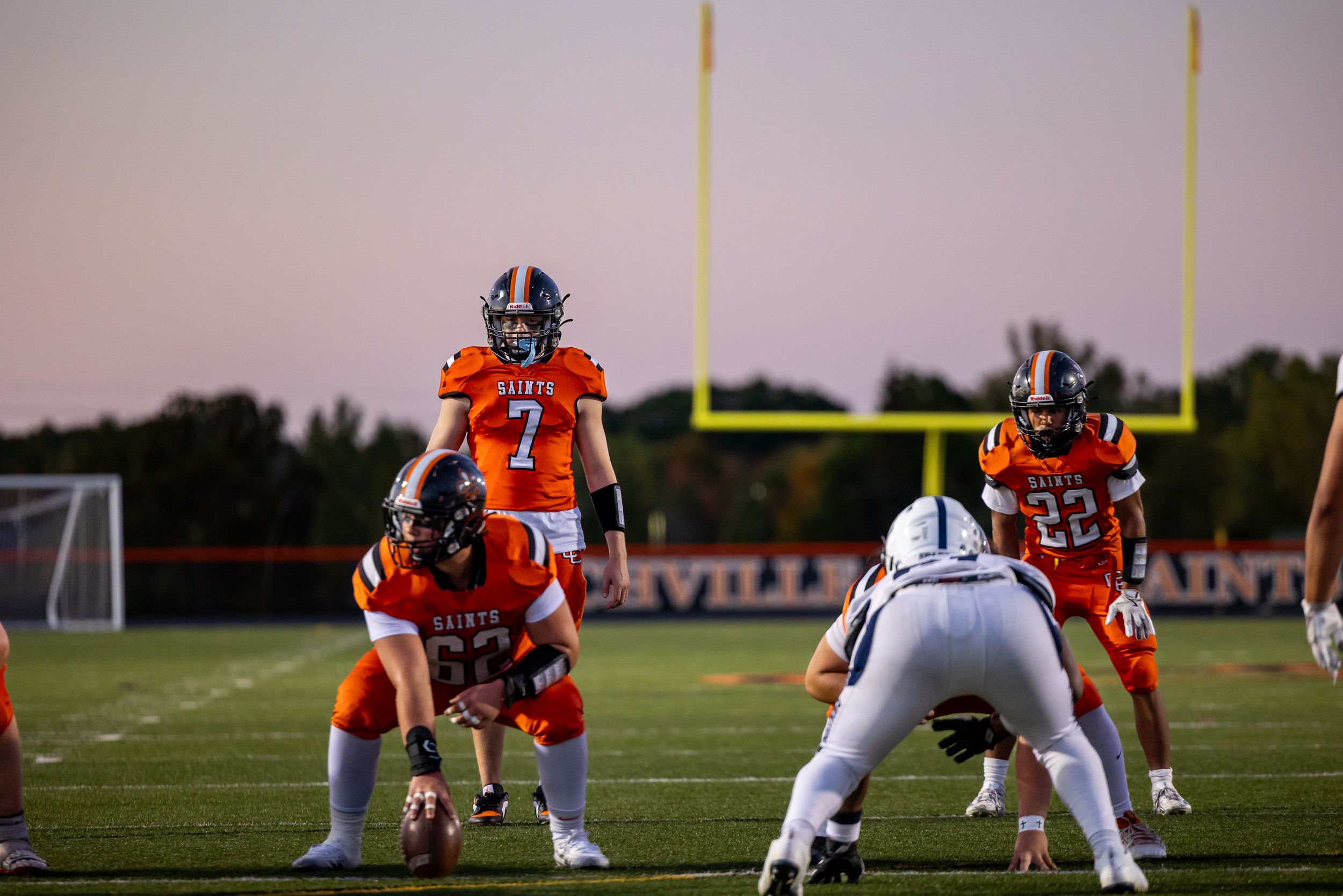 Football players in orange jerseys line up against opponents in white uniforms.