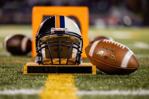 Football helmet and ball positioned on field with orange goal post in background.