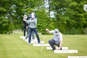 Golfers practicing their putting skills on a lush green course during a sunny day.