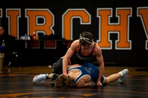 Wrestlers grappling during a competitive match on a gymnasium mat.