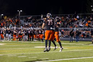 Two players celebrate on football field during nighttime game.