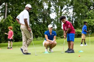 Golf instruction session with players practicing putting techniques on a green.