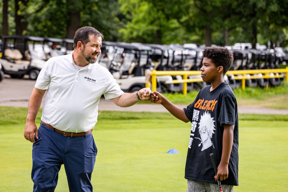 Golf instructor giving feedback to a young student on the putting green.