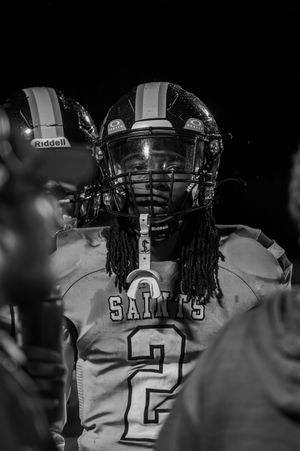 Close-up black and white portrait of football player wearing helmet with number 2 jersey.