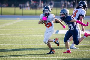 Football players in blue and white jerseys making tackles during an intense game.
