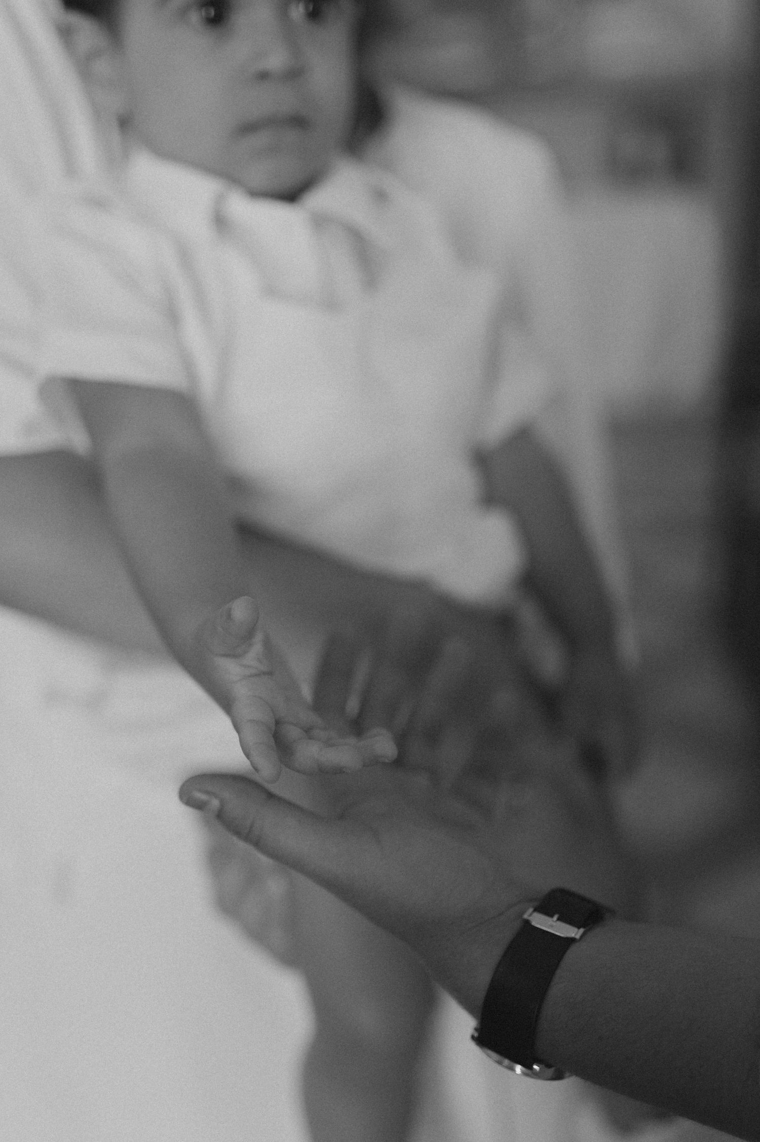 A black and white close-up of hands reaching towards each other.
