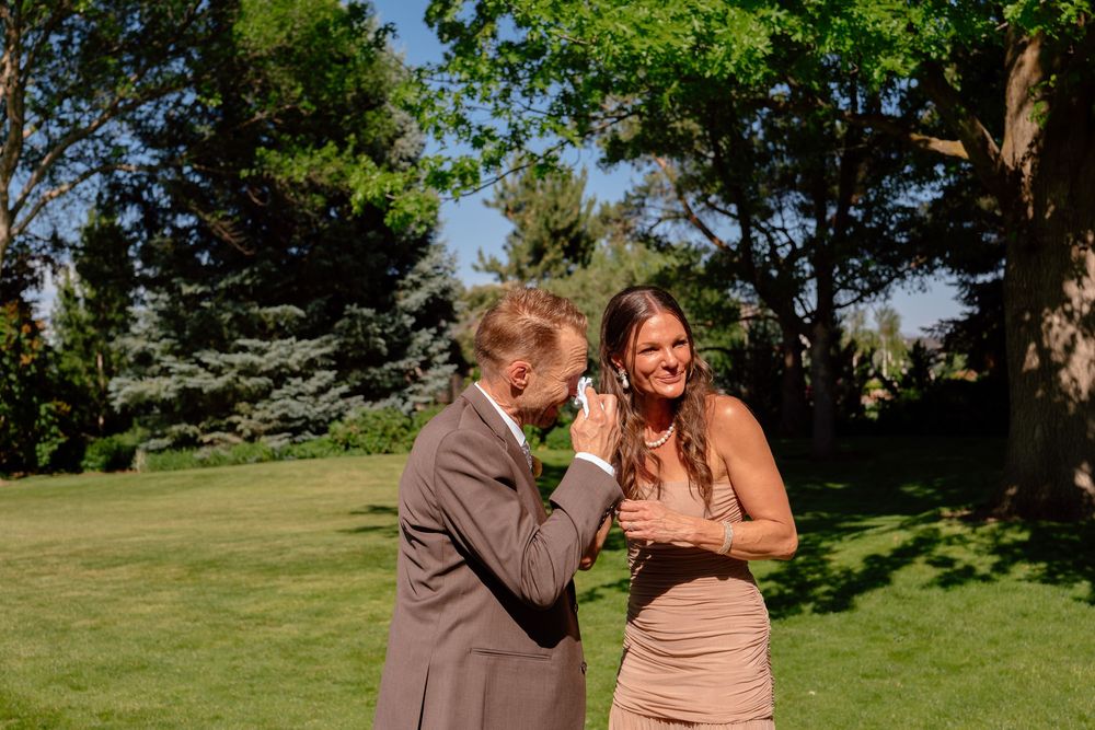 A couple shares a romantic moment together on a sunny lawn surrounded by trees and greenery.