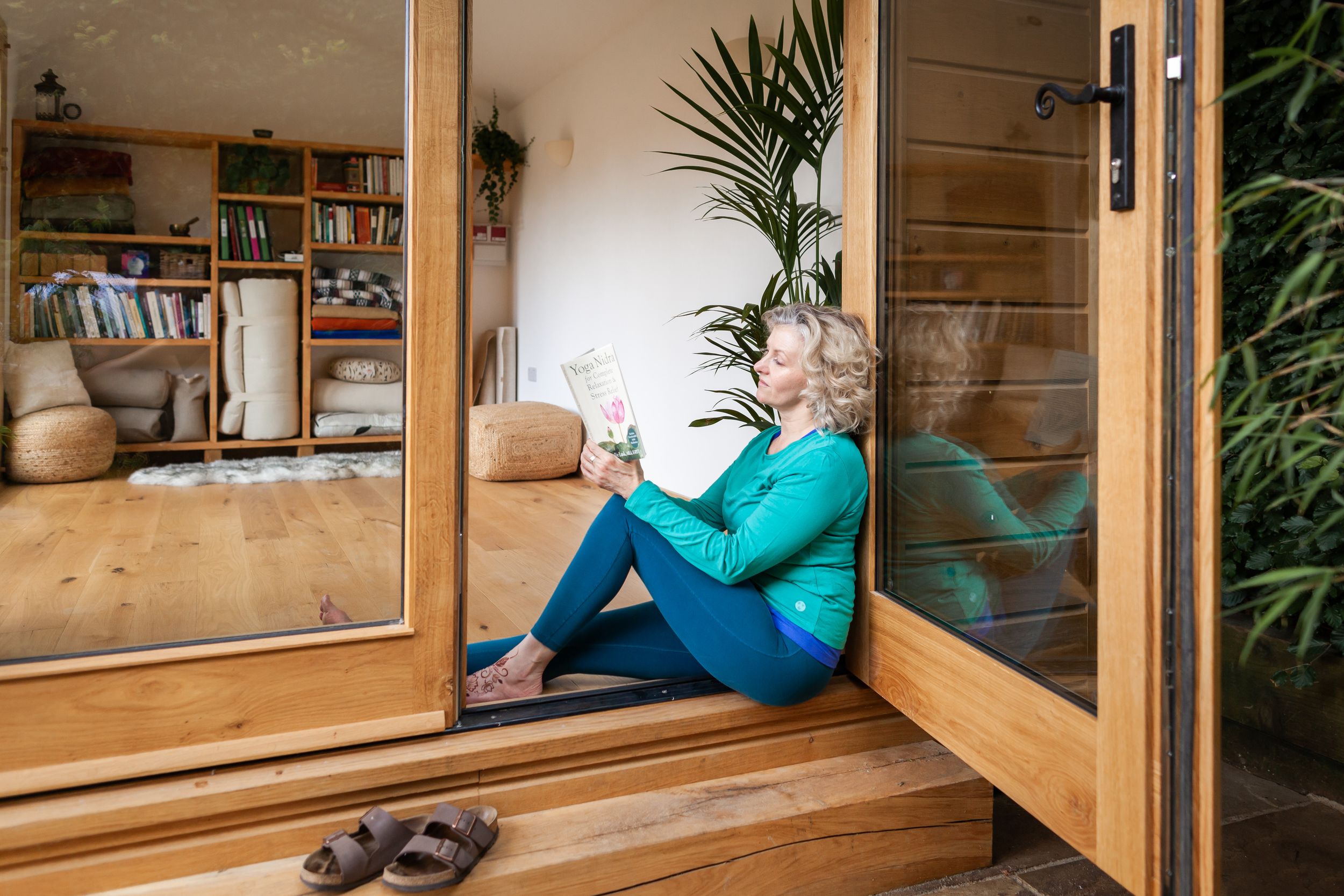 A cozy wooden reading nook with built-in shelving and cushioned seating by a large window with natural light.