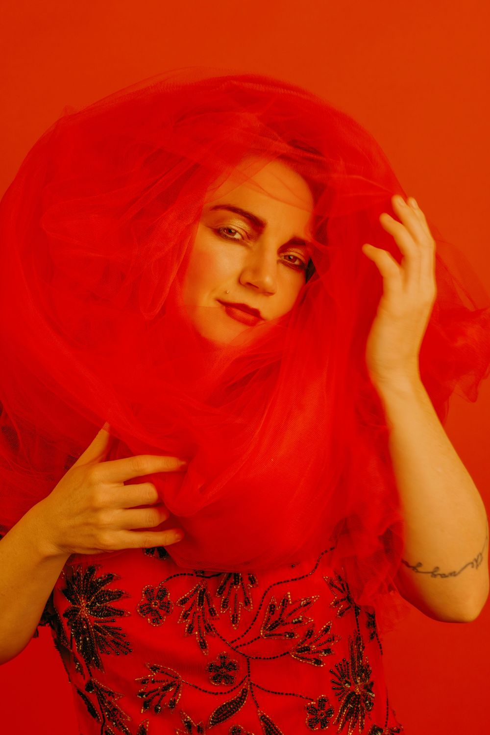Dramatic portrait series with flowing red fabric and floral pattern clothing against orange backdrop.